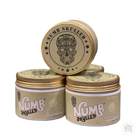 Three jars of Numb Skulled salve on a gray background